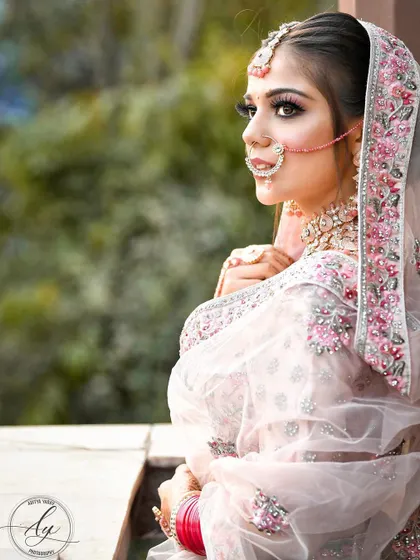 A beautiful profile shot of a bride looking out from a balcony. The soft natural light highlights her delicate features and the intricate details of her pink embroidered dupatta.