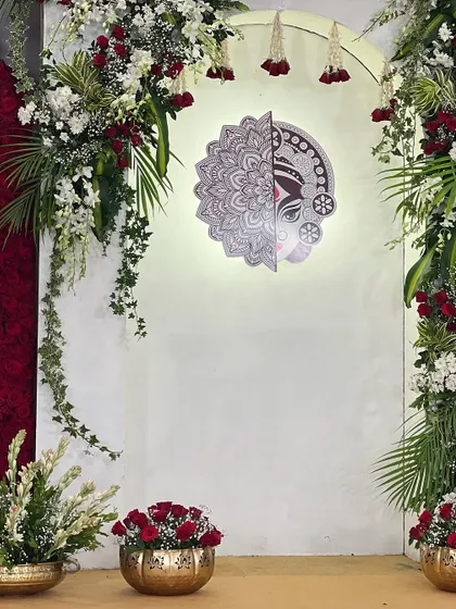 The illuminated Maa Durga art piece, framed by red roses and hanging florals. This was the heart of the "Mitakshi" naming ceremony, a beautiful representation of the baby's name.