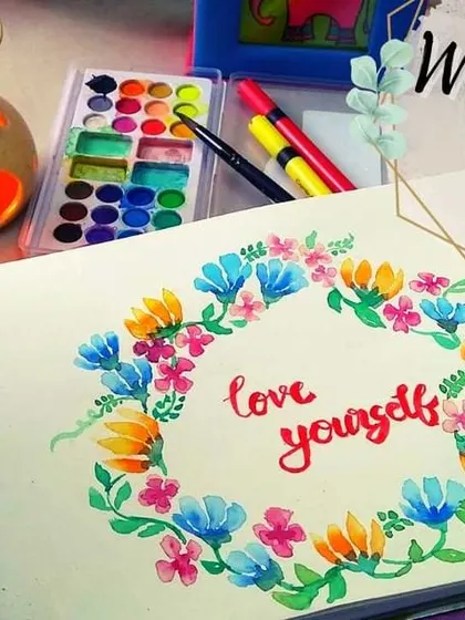 A watercolor floral wreath with the hand-lettered quote "love yourself" at its center. This is a perfect example of a personalized art piece that can serve as a beautiful daily reminder.