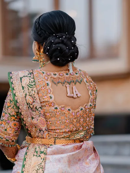 A classic bridal bun decorated with delicate pearls. This hairstyle provides a perfect canvas to showcase the intricate design of a custom bridal blouse.