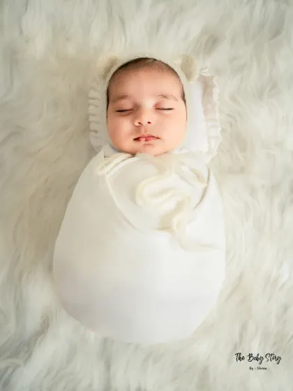 This 'egg wrap' pose is a beautiful way to show how newborns love to be curled up. The all-white setup is timeless and angelic.