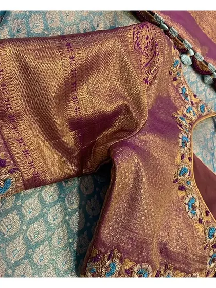 A close-up of the sleeve of the violet blouse, showing how the saree's border is incorporated into the design.