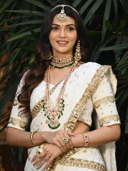 This look combines a traditional choker with a more modern layered haram, both featuring green and red stones. It is a great way to mix styles for a unique reception look.
