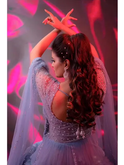 A graceful pose showing the beautiful back details of this powder blue gown. The delicate straps and flowing cape sleeves add a touch of ethereal beauty.