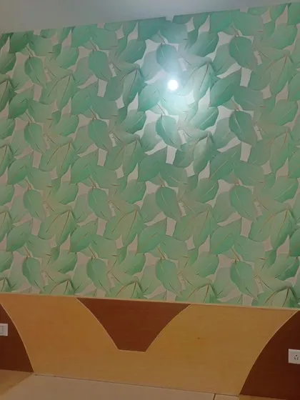 A bedroom accent wall featuring a large green leaf pattern. The design brings a fresh and natural vibe to the space.