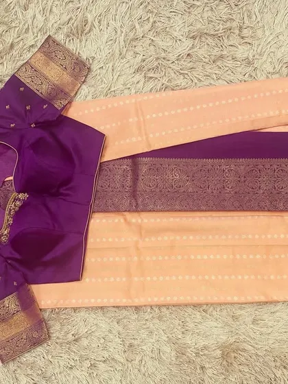 A lovely peach silk saree paired with a contrasting violet embroidered blouse.