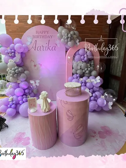 An elegant and simple butterfly-themed setup in shades of purple and grey, perfect for a sophisticated first birthday celebration.