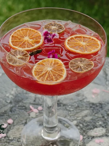 A close-up of our Sakura community cocktail, filled with dehydrated orange slices and edible flowers.