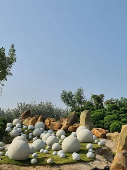 Another view of the unique Hyderabad landscape. The scattered white stone spheres look like giant eggs or pebbles, creating a playful and artistic contrast with the natural rocks and sculpted greenery.
