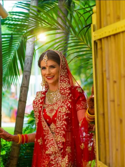 A stunning bride making her entrance. Her radiant smile and beautiful red lehenga capture the essence of a classic Indian bride.