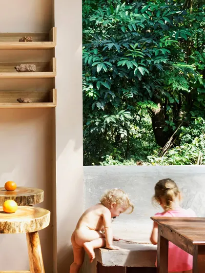 Children play by a large window that frames the dense Goan foliage, a scene that captures the essence of Unallome. The design seamlessly integrates the indoors with the outdoors, creating a space that feels open, natural, and full of life.
