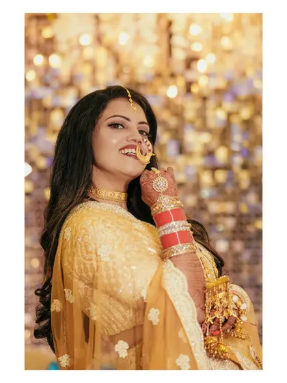 A stunning close-up of the bride, highlighting her beautiful smile, nath, and kaleerein. The bokeh background adds a magical touch to the portrait.