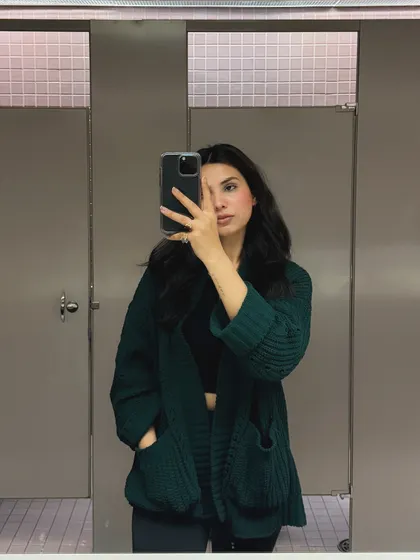A bathroom mirror selfie showing a cozy green cardigan, perfect for a casual day on campus. This raw, unpolished style feels very authentic.