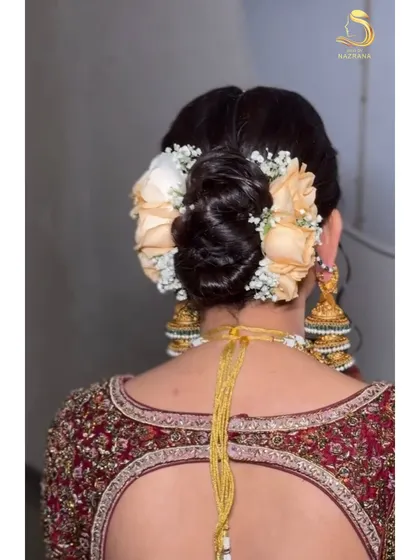 A beautiful floral bun featuring soft peach roses and baby's breath. This style is perfect for brides who want a romantic and classic look.