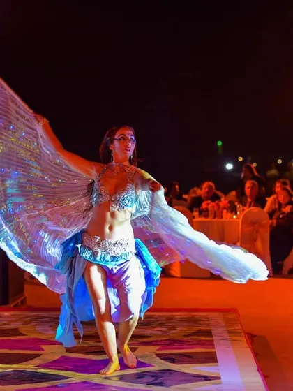 Entertainment that matches the destination. A belly dancer with iridescent wings performs at an Arabian-themed Sangeet night, providing guests with an authentic and memorable experience.