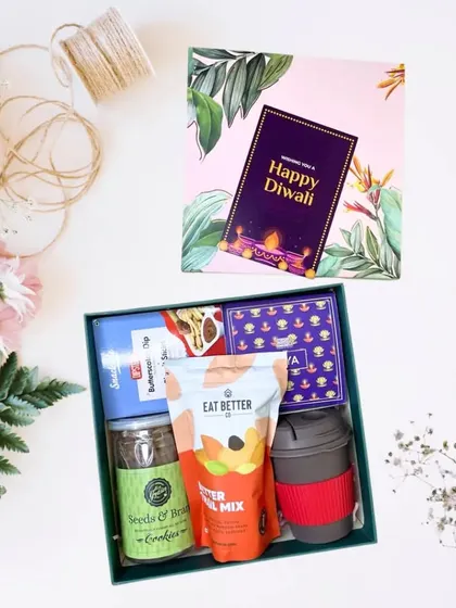 A beautifully arranged hamper in a green designer box. This set, starting from Rs.799, includes a reusable mug, trail mix, cookies, and other snacks.