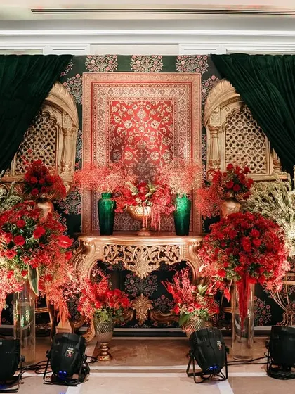 A rich composition of red florals, golden carvings, and emerald drapes creates a regal backdrop. This setup is a perfect example of how I layer textures and colors to achieve a look of balanced grandeur.