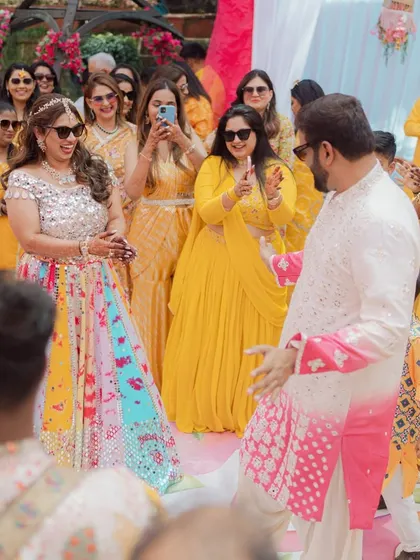 A fun and colorful Haldi celebration. The couple is surrounded by their guests, all dressed in shades of yellow, creating a vibrant and joyful picture.