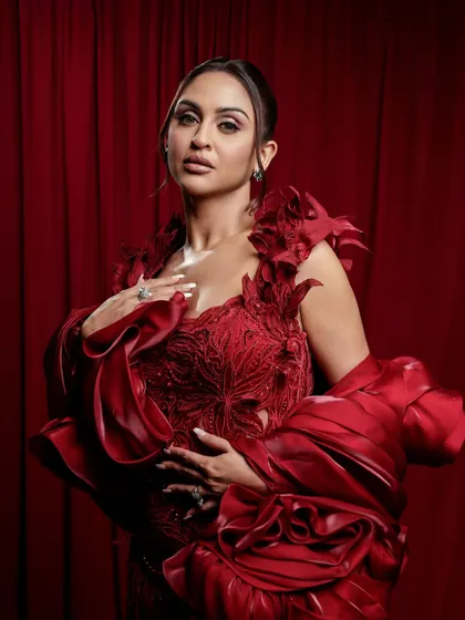 A close-up of the dramatic red gown look. The makeup is kept elegant and defined, with a focus on flawless skin to let the outfit be the hero.