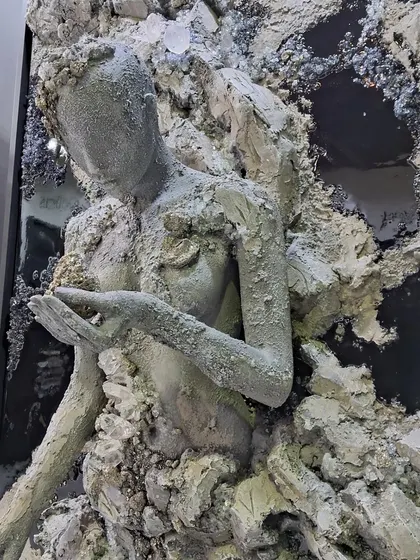 A sculpture by Maria Molaei depicting a figure emerging from rough, stone-like textures.