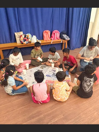 A view from behind shows a circle of children completely absorbed in their craft project. Our classes are designed to be engaging, allowing kids to focus and enjoy the creative process.