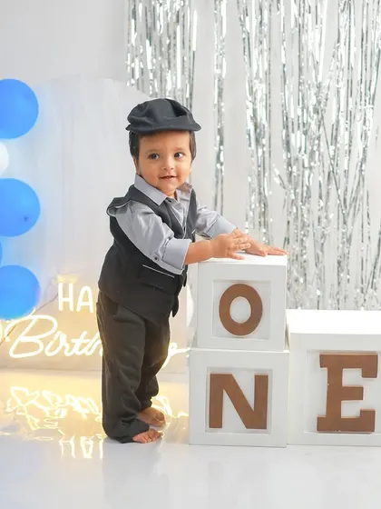 Dressed in a dapper vest and cap, this little boy looks so charming as he stands by his 'ONE' blocks. It's a classic and timeless way to commemorate the first birthday.