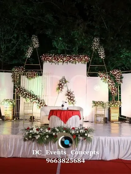 A minimalist yet elegant stage for an outdoor wedding reception. The clean white panels, subtle floral accents, and open design complement the natural surroundings perfectly.