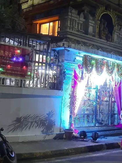 The entrance to a temple decorated for a festival night. The lights and drapes make the entrance look grand and inviting.