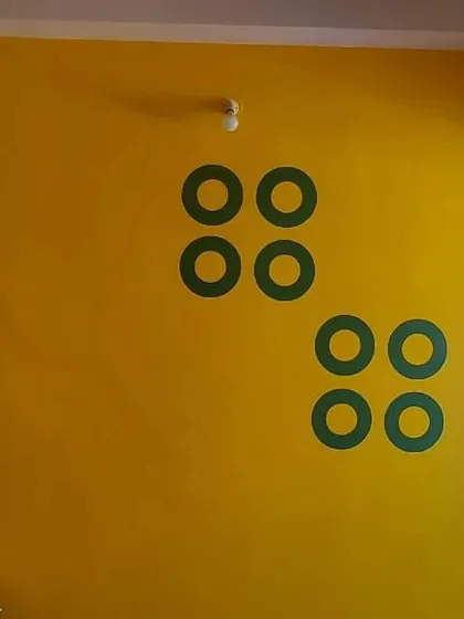 A simple yet effective geometric design using green ring stencils on a bright yellow wall, adding a pop of modern, minimalist art.