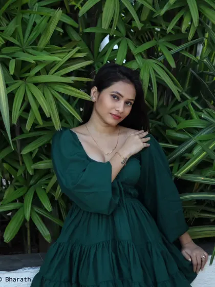 A relaxed and happy outdoor portrait against a wall of green leaves. The natural light is soft and flattering.