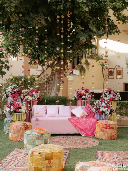 The full view of our 'Love & Laughter' Mehendi setup, with a tree adorned with hanging flowers and a cozy, colorful seating arrangement.