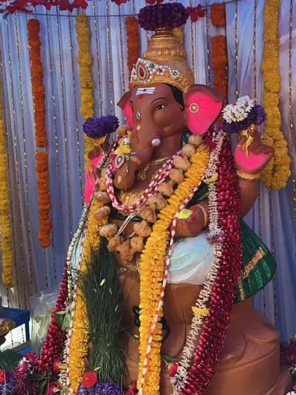 A close-up of a Ganesha idol decorated with multiple flower garlands for a festival.