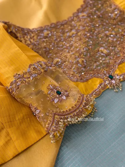 A yellow blouse with sheer sleeves, featuring floral motifs and pearl tassels.