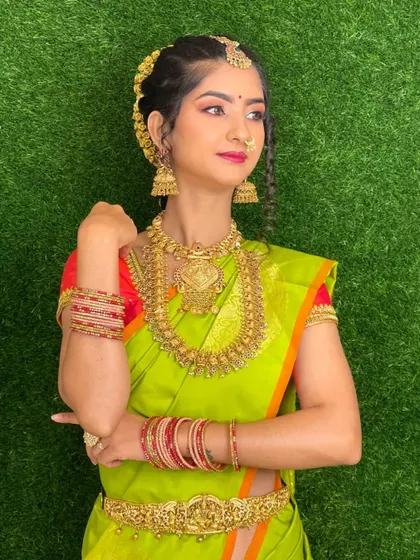 This profile shot highlights the traditional braided hairstyle with gold accessories and the detailed craftsmanship of the temple jewelry.