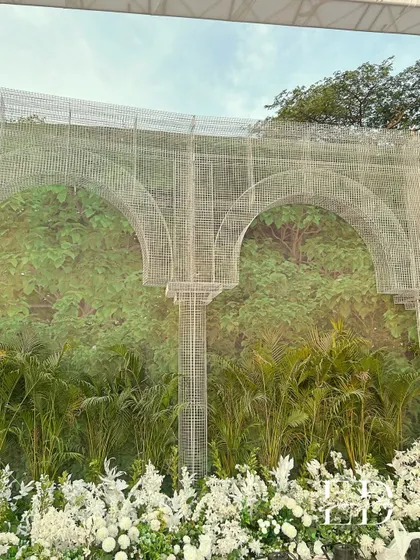 The texture of the wire mesh structure contrasts beautifully with the soft, organic forms of the white flowers and green plants below. This is a core element of my sustainable design philosophy.