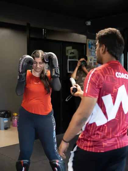 A coach gives one-on-one instruction to a female fighter, correcting her guard and stance. Personalized feedback is key to improvement.
