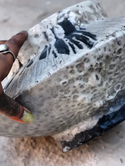 A participant holding their finished Raku piece. The smoky, carbon-blackened clay contrasts beautifully with the white crackle glaze, a signature look of the Raku technique.