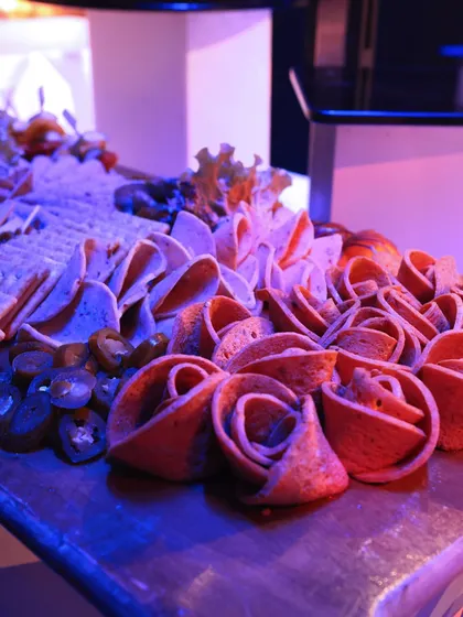 A charcuterie board featuring salami roses and jalapeños. This creative presentation adds a touch of artistry to a classic offering, making it a standout feature on the buffet.