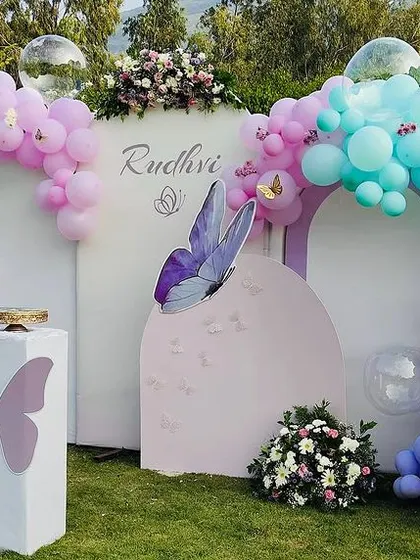 The full view of the outdoor butterfly party decor, showing the multiple arched panels and balloon garlands.