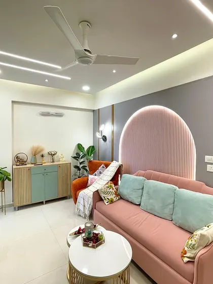This living room features a beautiful blend of pastel colors and modern furniture. The blush pink sofa, set against a gray accent wall with a ribbed arch detail, creates a chic and inviting focal point.