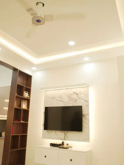 A minimalist living room with a simple floating TV unit against a marble back panel. The design is clean, uncluttered, and focuses on the beauty of the materials.