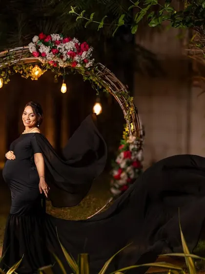 The circular floral arch lit up at night provides a beautiful frame for this elegant portrait in a black gown.