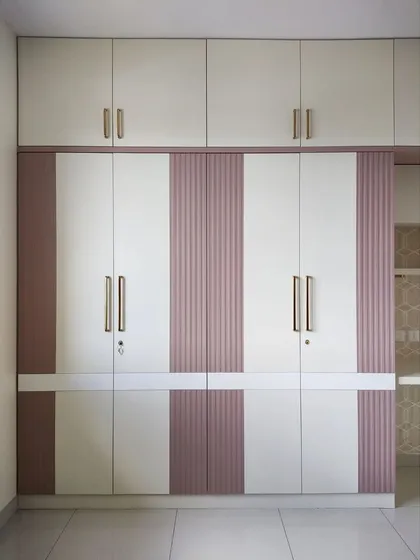 The full view of the pink and white wardrobe with fluted panel details and sleek gold handles, offering a look of simple luxury.
