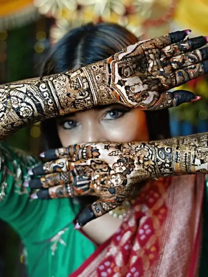 A beautiful, artistic pose from a bride showcasing her full arm henna. The intricate patterns, from the palms to the elbows, are designed to complement her entire bridal look.