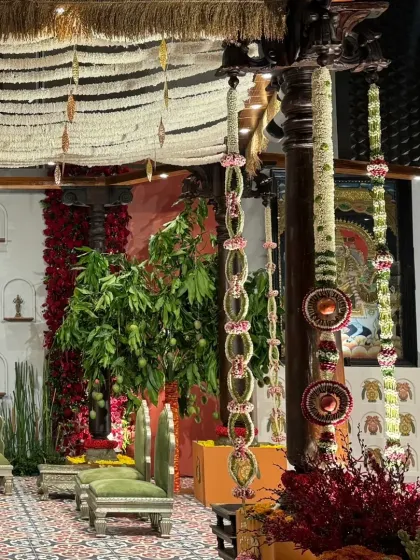 A side view of the 'Divya Stambh' stage, showcasing the layers of tradition. From the hand-carved wooden pillars to the floral-adorned chairs and traditional tiled flooring, every element contributes to the divine narrative.