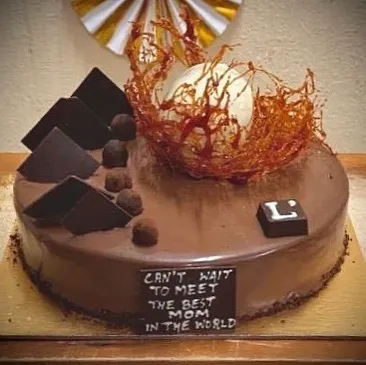 We bake for your most cherished moments. This custom Belgian Truffle Cake was designed for a baby shower, complete with a delicate spun sugar nest. We love adding a touch of artistry to your celebrations.