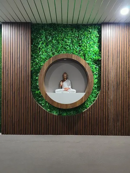 A serene meditation nook featuring a Buddha statue set against a backdrop of vertical garden panels and wooden fluting. This tranquil corner is designed to be a peaceful escape within the home.