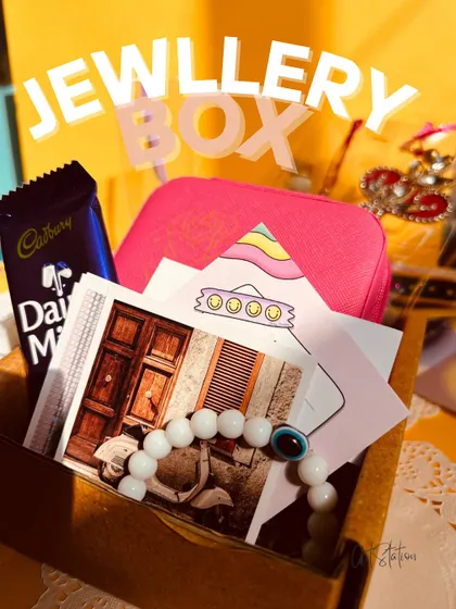 A personalized jewellery box can be the centerpiece of a thoughtful gift hamper. Here, a pink box is included with chocolates, photos, and other small treats, creating a complete and personal gift package.