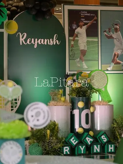 A close-up of the tennis-themed stage decor, featuring photos of tennis stars, themed props, and personalized letter blocks.
