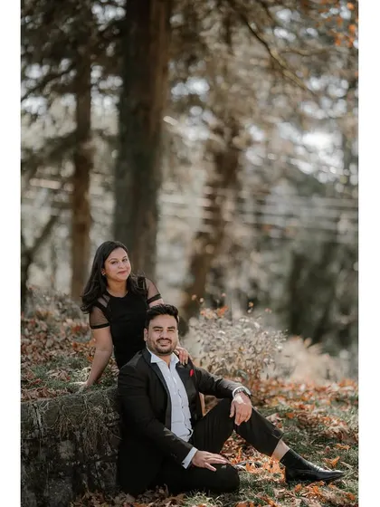A relaxed portrait of a couple sitting in a forest clearing. This shot captures a quiet, comfortable moment during their pre-wedding session.